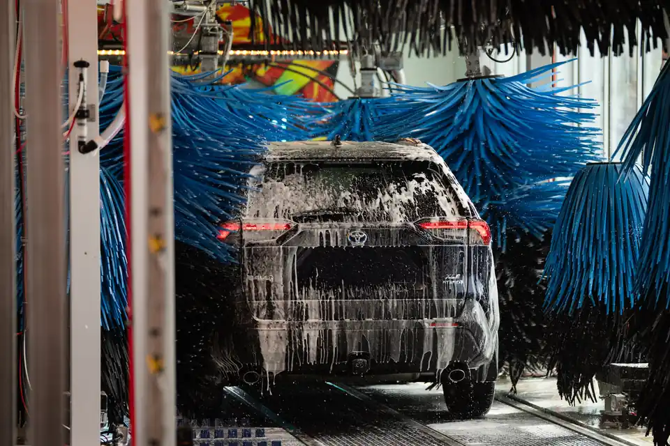 An SUV covered in foam passing between the soft closed-foam brushes inside the wash tunnel